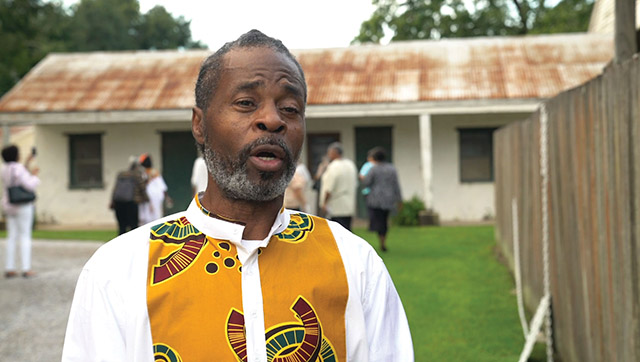 Leroy Hawkins, descendant of enslaved people held by the Society of the Sacred Heart, stands before the former quarters where his ancestors lived.