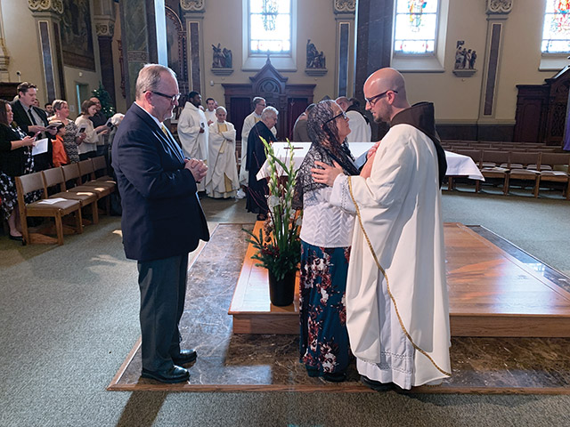 The newly ordained Father M.J. Groark, O.F.M.Cap. performs his first priestly blessing upon his mother, Anna.