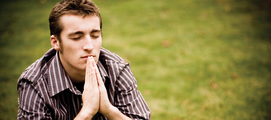 young man praying in a field