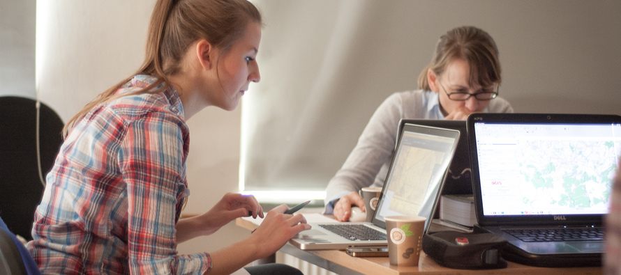 Two female high-school age students working on laptops. Photo by Sebastian Sikora.