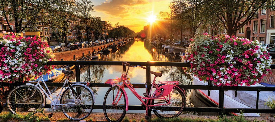 Bicycles parked in front of a canal with the sunset in the background