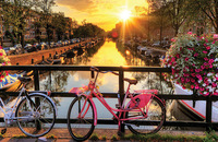 Bicycles parked in front of a canal with the sunset in the background