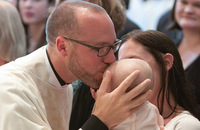 Father Paddy Gilger, S.J. gives a kiss to his goddaughter and niece, Hayden Bauer.