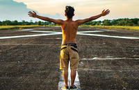 Young man standing in road with his arms open wide